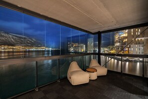 Ein modernes Interieur mit großen Fenstern, einem Balkon und Sitzgelegenheiten.