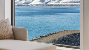 A room with a large window overlooking a body of water and snow-capped mountains. - Premium Waterfront Apartment–Sea & Mountain View (Tromsø)