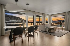 Ein modernes Wohnzimmer mit Essbereich, großen Fenstern mit Bergblick und einer gemütlichen Sitzecke.