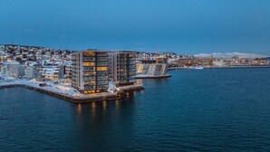 A waterfront hotel with modern architecture, a dock, and a view of the cityscape. - Premium Waterfront Apartment–Sea & Mountain View (Tromsø)