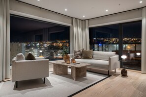 Ein modernes Wohnzimmer mit einer Couch, einem Couchtisch und großen Fenstern mit Blick auf die Stadt.