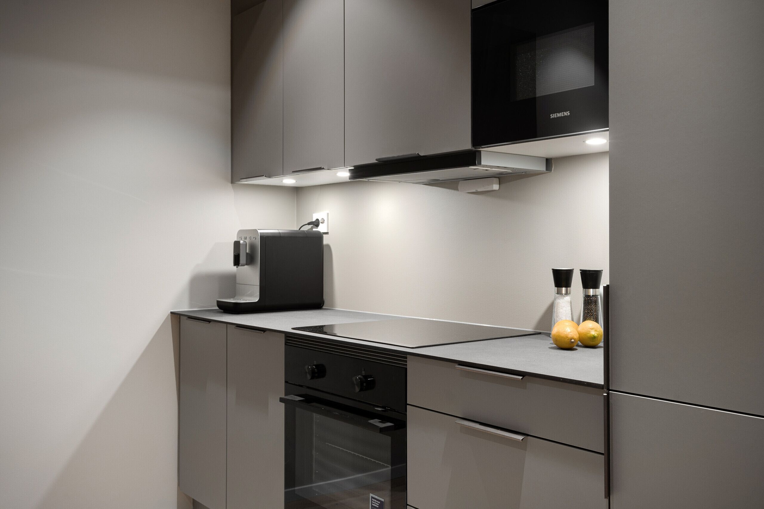 Una cocina moderna con horno empotrado, cafetera y microondas.