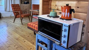 A rustic cabin interior with a wood stove, two plaid chairs, and a wooden cabinet. - Lofoten Horizon, Fredvang (Flakstad)