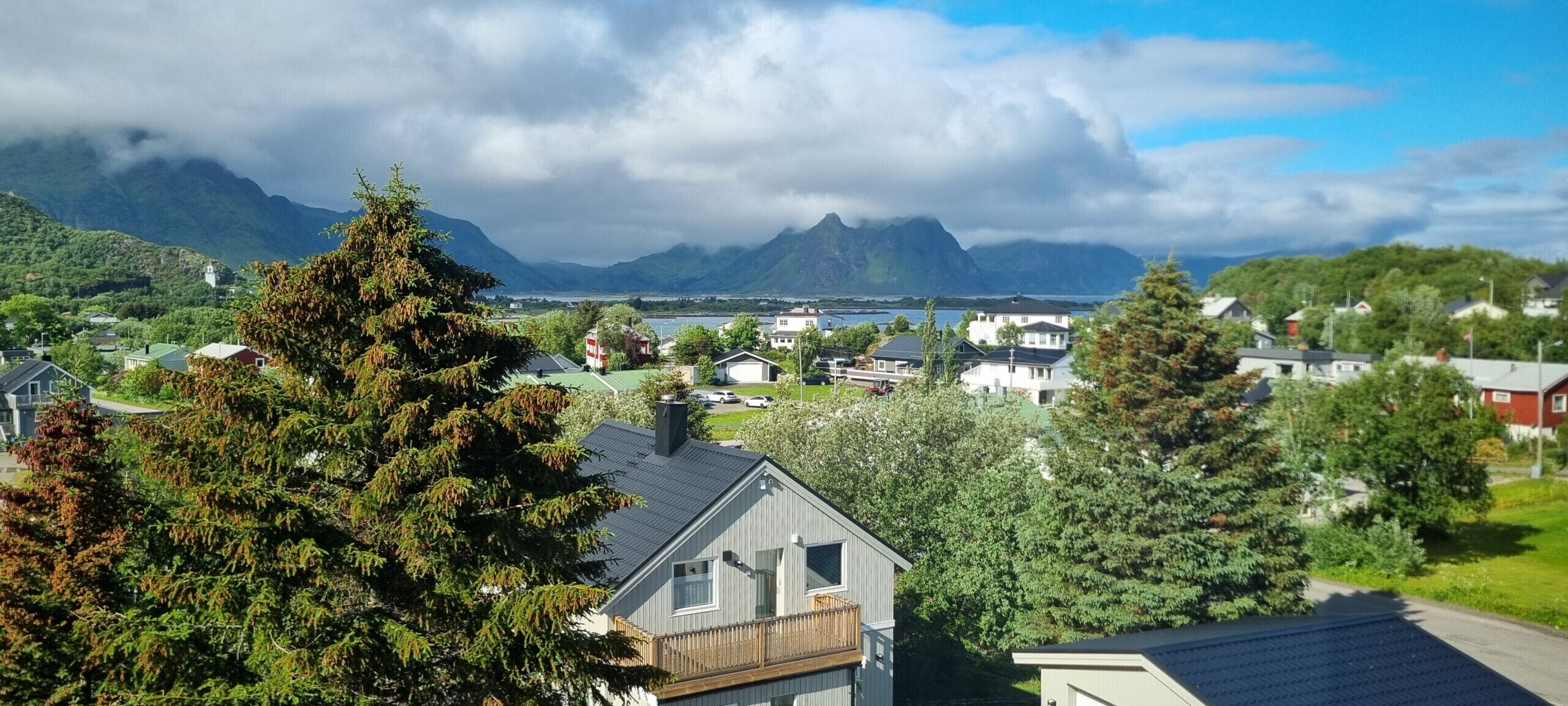 A residential area with houses, a mountain backdrop, and a body of water.