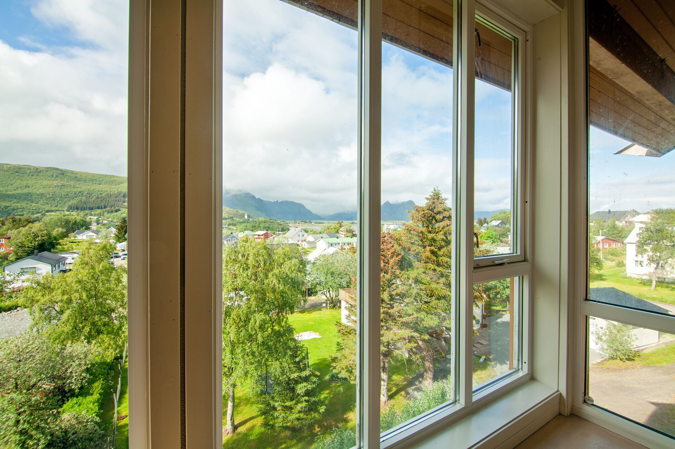 Una habitación con un ventanal que ofrece vistas a un paisaje verde y montañas a lo lejos.