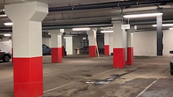 Autotalli, jossa on betonipilarit, märkä lattia ja kauempana näkyvä auto.