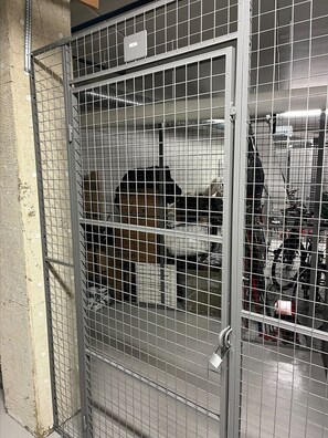 Ein Metallgitter mit Schloss, Maschendraht und einer weißen Tür.