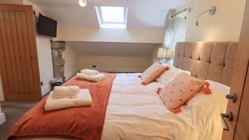 A bedroom with a bed, a TV, a window, a shower, and a door.
