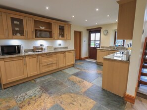 A modern kitchen with wooden cabinets, a microwave, toaster, and a bread box. - Orcaber Farm Barn (Lancaster)