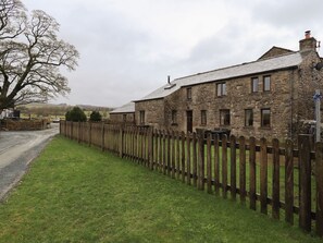 A stone building with a wooden fence, a gravel path, and a tree. - Orcaber Farm Barn (Lancaster)