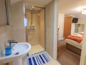 Une salle de bain avec une douche à parois de verre, un lavabo blanc et une serviette bleue sur le sol.