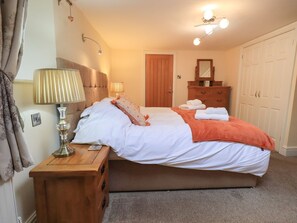 Ein Schlafzimmer mit einem Bett, Nachttischlampen, einem Schminktisch, einem Spiegel und einem Kleiderschrank.