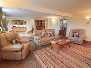 A living room with a sofa, armchair, and ottoman, a coffee table, and a patterned rug. - Orcaber Farm Barn (Lancaster)