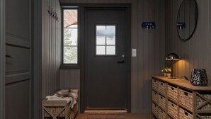 A hallway with a wooden bench, a door, a wall-mounted lamp, and wicker baskets.