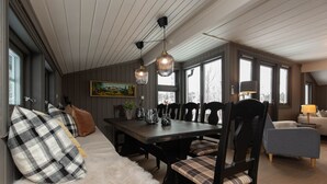 A dining area with a wooden table, chairs, and pendant lights.