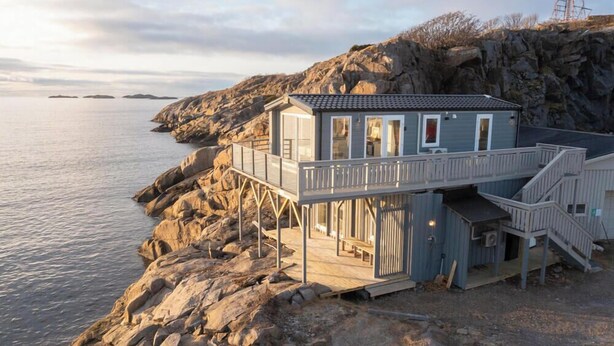 A coastal house with a balcony, a staircase, and a view of the sea.