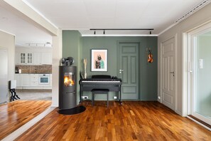A room with a piano, a fireplace, and a door with a violin hanging on it. - Trivelig leilighet i rolige, bynære omgivelser (Tromsø)