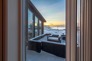 A view from a room with large windows overlooking a snowy landscape and a sunset.