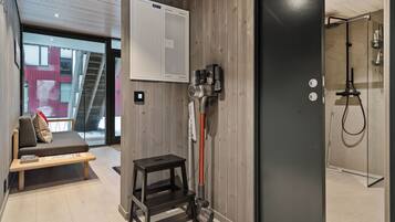 A modern bathroom with a shower, a bench, and a vacuum cleaner.