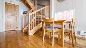 A wooden staircase with a view of the outside, a dining table with chairs, and a window with blinds.