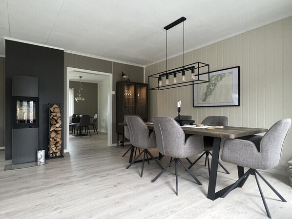 A modern dining area with a wooden table, grey upholstered chairs, and a pendant light.