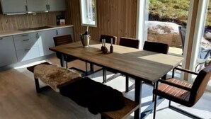 A modern kitchen with wooden cabinets, a dining table with chairs, and a bench.