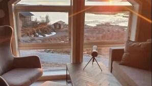 A room with a large window, a tripod, and a wooden table.