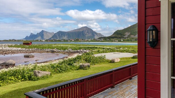 A red building with a view of mountains and a body of water.