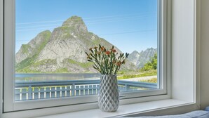 A window with a view of a mountain and a body of water.