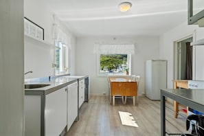 A compact kitchen with a window, a wooden table, and a refrigerator.