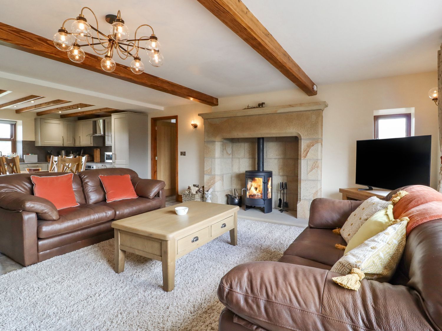A living room with a fireplace, leather sofas, a coffee table, and a TV.