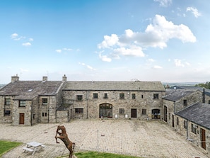 Un edificio de piedra con un patio, una escultura de caballo y una mesa de picnic.
