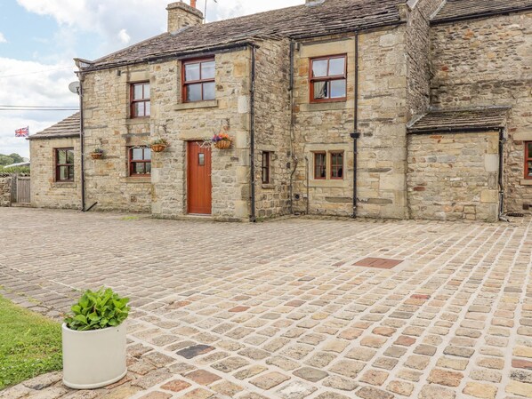 A stone building with a red door, multiple windows, and a paved courtyard. - Orcaber Farmhouse (Lancaster)