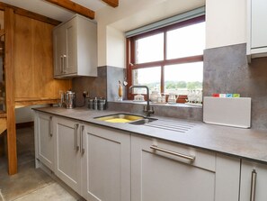 A kitchen with a sink, cabinets, a window, and a refrigerator.