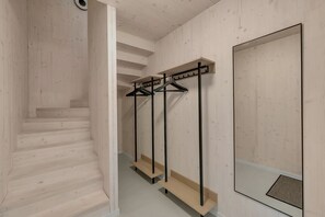 A wooden interior with a staircase, a mirror, and a clothing rack.