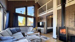 A modern living room with a sofa, television, and a wood-burning stove.