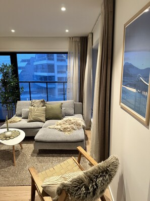 Un salon moderne avec un canapé gris, une petite table ronde et une chaise en bois.