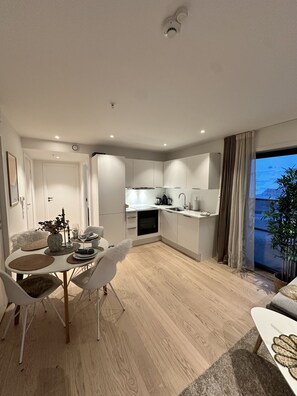 Un appartement moderne comprenant un coin repas, une cuisine et une grande fenêtre avec des rideaux.