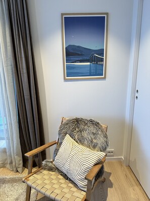 A room with a chair, a framed picture on the wall, a curtain, and a carpet. - Modern apartment in Tromsø (Tromsø)