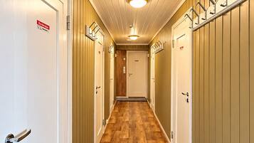 Un couloir doté d’un plancher en bois, de portes blanches et d’un plafond agrémenté d’un luminaire central.