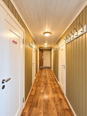 A hallway with wooden flooring, white doors, and a ceiling with a central light fixture.