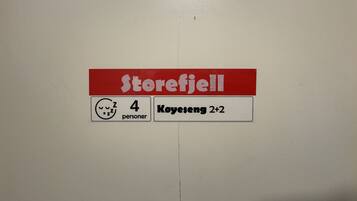 A sticker on a wall with the text 'Storefjell' and '4 personer' indicating the store name and capacity.