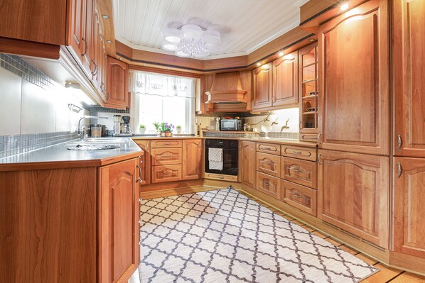 A kitchen with wooden cabinets, a microwave, a stove, and a patterned rug.