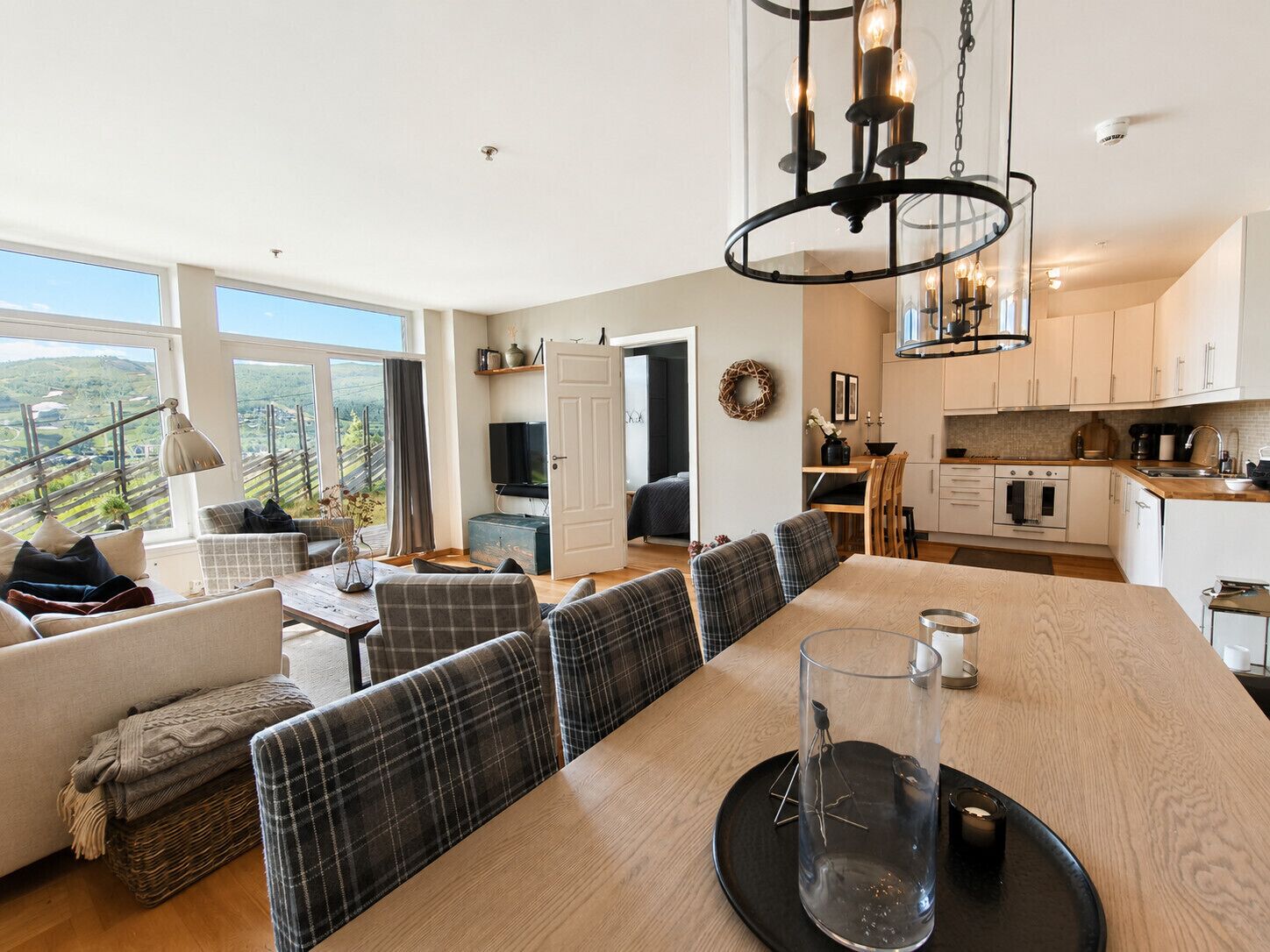 A modern kitchen with a dining area, large windows, and a view of the countryside.