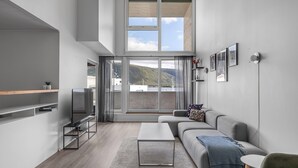 A modern living room with a sofa, TV, and a large window with a view of a mountain. - Central apartment with seaview, Tromsø (Tromsø)