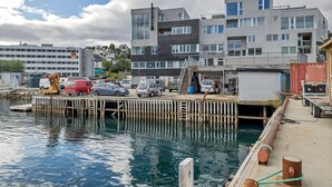 A waterfront dock with vehicles, a crane, and modern buildings in the background. - Central apartment with seaview, Tromsø (Tromsø)