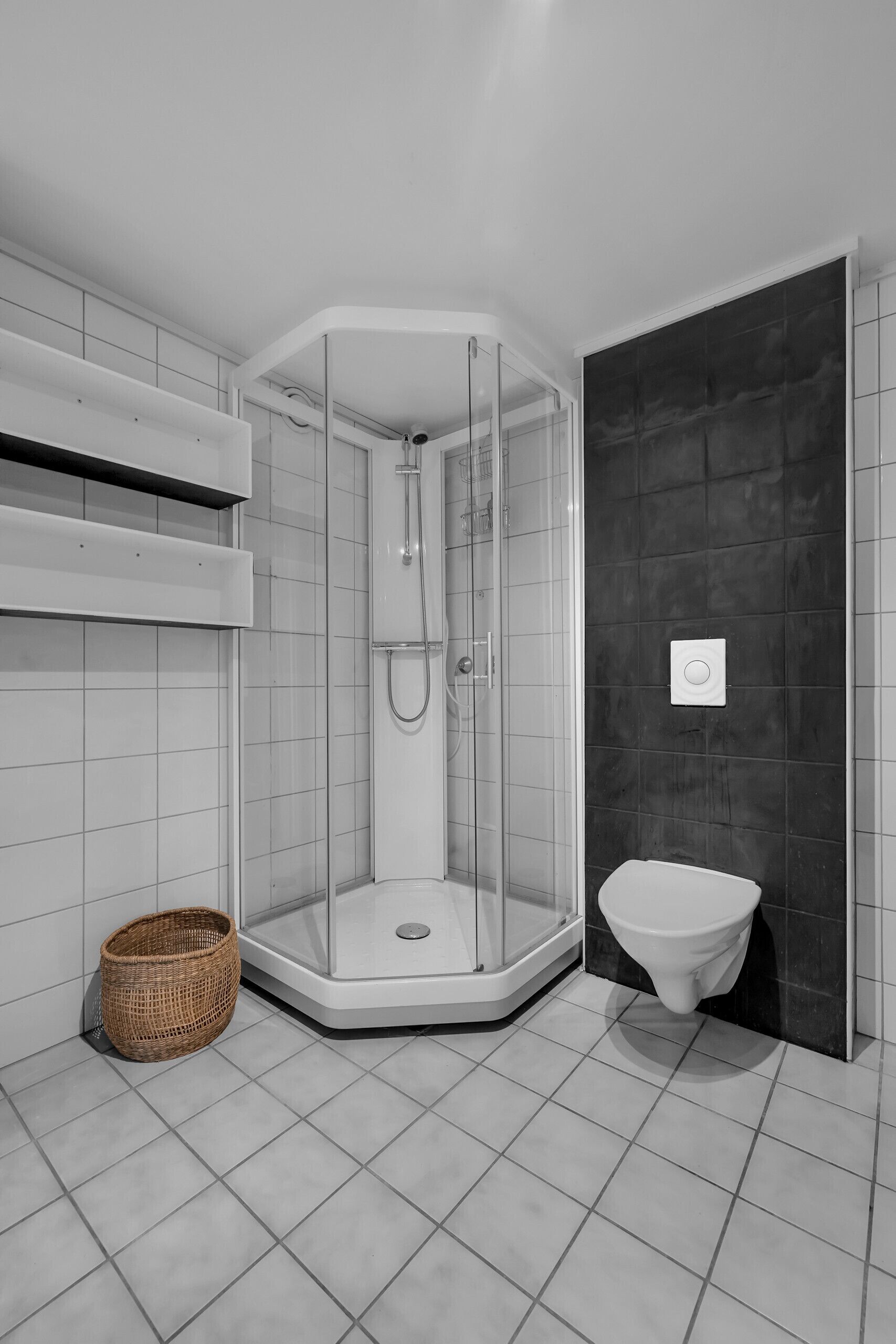 Une salle de bain moderne avec une douche à parois de verre, des toilettes blanches et un sol carrelé.