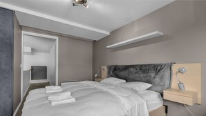 A modern hotel room with a large bed, bedside tables, a headboard, and a built-in shelf. - Central apartment with seaview, Tromsø (Tromsø)