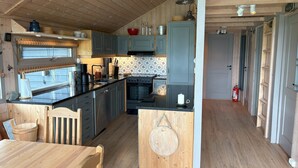 A kitchen with wooden cabinets, a stove, and a dining area with a table and chairs.