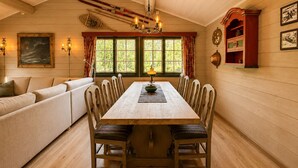 A cozy room with a wooden dining table, chairs, a sofa, and a chandelier. - Briskebu, cosy cabin by ski slopes (Hol)